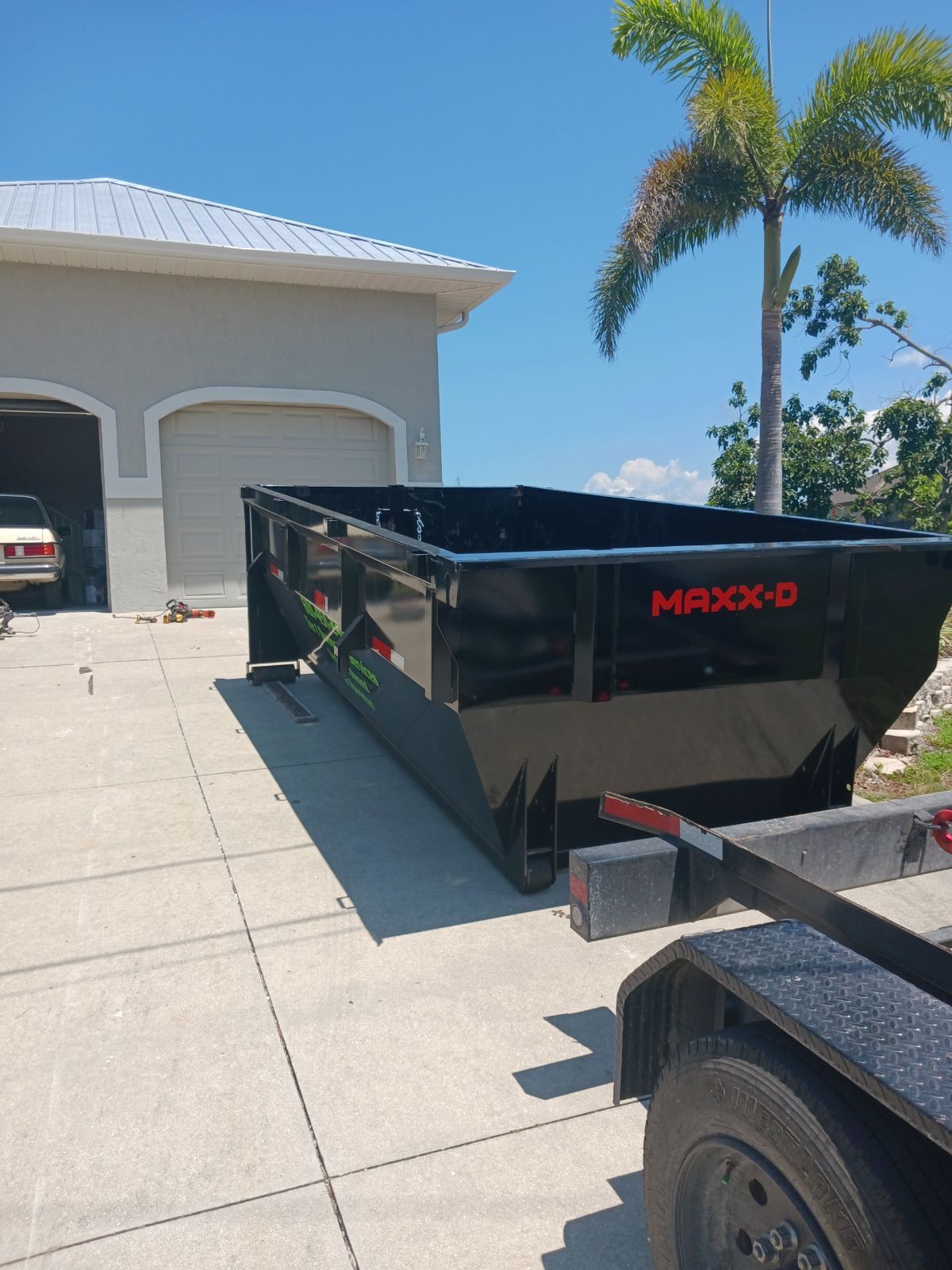 Dumpster Rental being dropped off in a driveway located in Naples FL